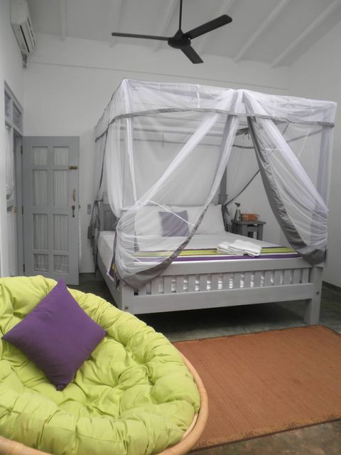 A canopied bed with a ceiling fan above it in a room at EKA Beach
