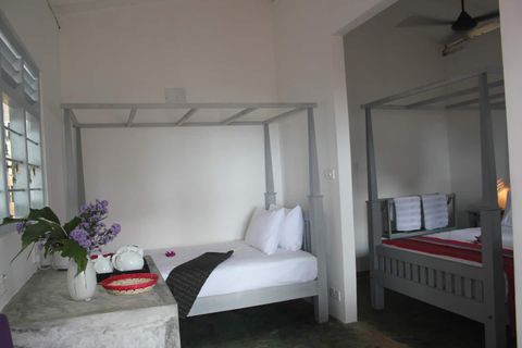 The interior of a room at EKA Beach with canopied beds and tiled floors