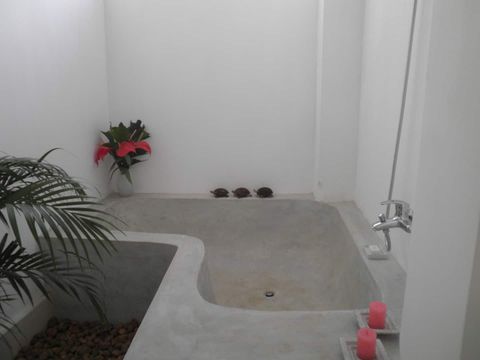 A bright open-air style en-suite bathroom with plants at EKA Beach