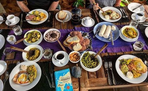 A Sri Lankan breakfast laid out across a timber table at EKA Beach: string hoppers, dhal, coconut sambol, curries, red rice, eggs, fresh bread and coffee