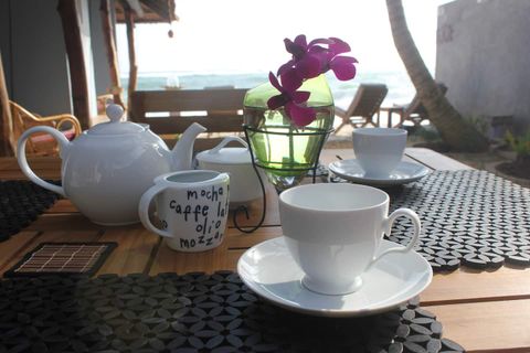 A teapot, cups, fruit and an orchid on a breakfast table at EKA Beach