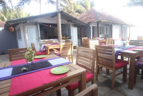 Timber dining tables with bright cushions on the shared terrace at EKA Beach