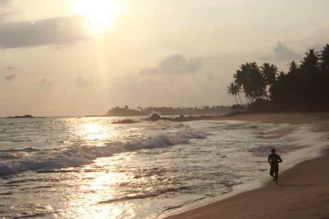 A person walking on the beach at sunset in front of EKA Beach, Talpe