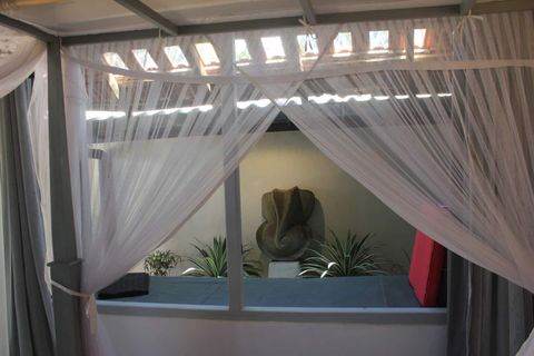 A canopied bed beneath a slatted timber roof at EKA Beach